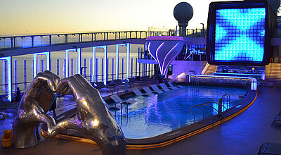 Auch vier Schiffe der stylischen Edge Class, hier die Celebrity Apex, werden in der Karibik eingesetzt. Foto: ck Pool auf bunt beleuchtetem Kreuzfahrtschiff
