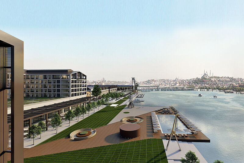 Ein modernes Gebäude am Wasser mit einer weitläufigen Uferpromenade, begrünten Flächen und luxuriösen Freizeiteinrichtungen. Im Vordergrund befinden sich ein großer Pool mit Sonnenliegen, Holzdecks und Sitzgelegenheiten. Entlang der Promenade reihen sich Bäume, moderne Gebäude mit großen Fenstern und Terrassen sowie überdachte Gehwege. Im Hintergrund fließt ein breiter Fluss mit Booten, und auf der gegenüberliegenden Seite ist die historische Skyline von Istanbul mit Moscheen und Brücken zu sehen.