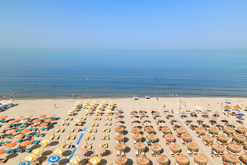 Sandstrand mit Sonnenschirm und liegen dahinter das Meer