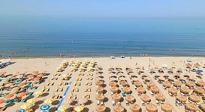 Sandstrand mit Sonnenschirm und liegen dahinter das Meer