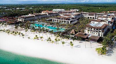 Ein großes Hotelgebäude an einem feinsandigen Strand.