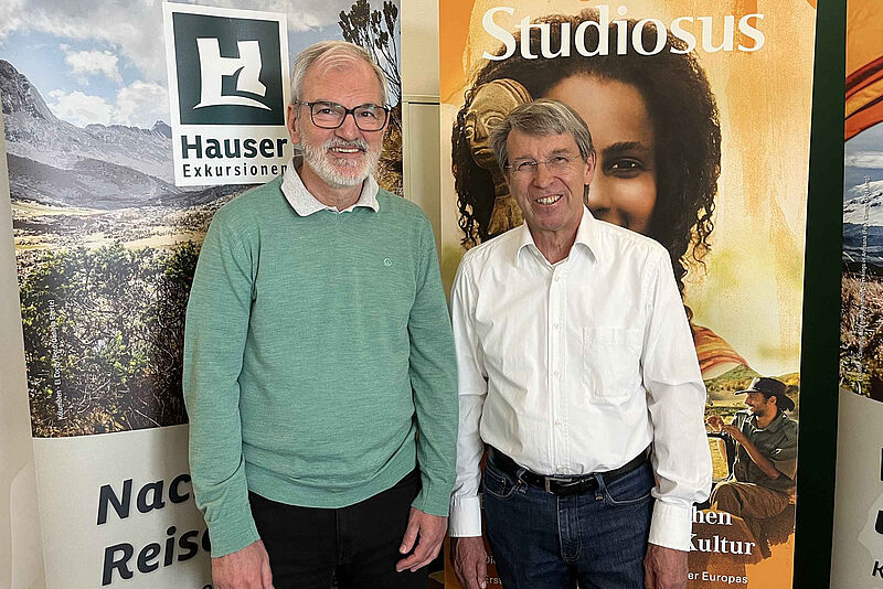 Hauser Exkursionen mit Geschäftsführer Manfred Häupl (links) gehört ab sofort zur Unternehmensgruppe Studiosus um Geschäftsführer Peter-Mario Kubsch (rechts) Manfred Häupl und Peter-Mario Kubsch vor Aufstellern von Hauser Exkursionen und Studiosus