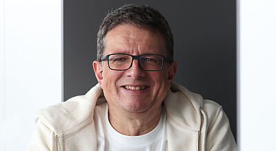 Porträt eines Mannes mittleren Alter in einem weißen T-Shirt und beigen Kapuzenpulli