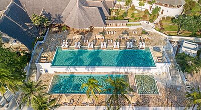 Luxuriöse Hotelanlage mit großen Pools, Sonnenliegen und Palmen im tropischen Urlaubsziel Sansibar – ein guter Ort zum Entspannen mit Blick auf den Indischen Ozean.