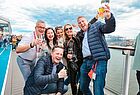 Ein Gruppenbild von mehreren Menschen, die zum Teil Gläser mit Getränken in der Hand halten