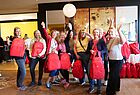 Mehrere Frauen stehen in der Lobby eines Hotels und halten rote Rucksäcke der Fluggesellschaft Emirates.