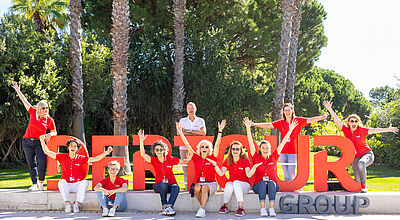 Touristiker-Gruppe vor Dertour-Logo