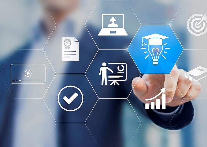 Ein Geschäftsmann in Anzug berührt ein digitales Interface mit hexagonalen Symbolen zu Weiterbildung, E-Learning und beruflicher Entwicklung, darunter Laptop, Zertifikat, Präsentation, Wachstumsgrafik und eine Glühbirne mit Doktorhut.