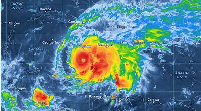 Satellitenbild eines Hurrikans über der Karibik, das den Wirbelsturm mit seinem klar erkennbaren Auge nahe Kingston, Jamaika, zeigt – farbcodierte Wetterkarte mit starken Niederschlägen und dichten Wolkenbändern über der Karibik, Haiti und der Dominikanischen Republik