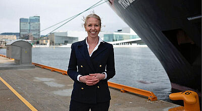 Hurtigruten-CEO Hedda Felin sieht in der Übernahme eine „solide finanzielle Basis, um nachhaltig zu wachsen“ Hurtigruten-Chefin Hedda Fenin vor Schiffsbug