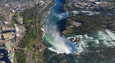 Die wasserreichen Niagarafälle an der Grenze von Kanada und den USA aus der Vogelperspektive. Vorn im Bild sind die Horseshoe Falls zu sehen, hinten die Bridal Vail Falls.