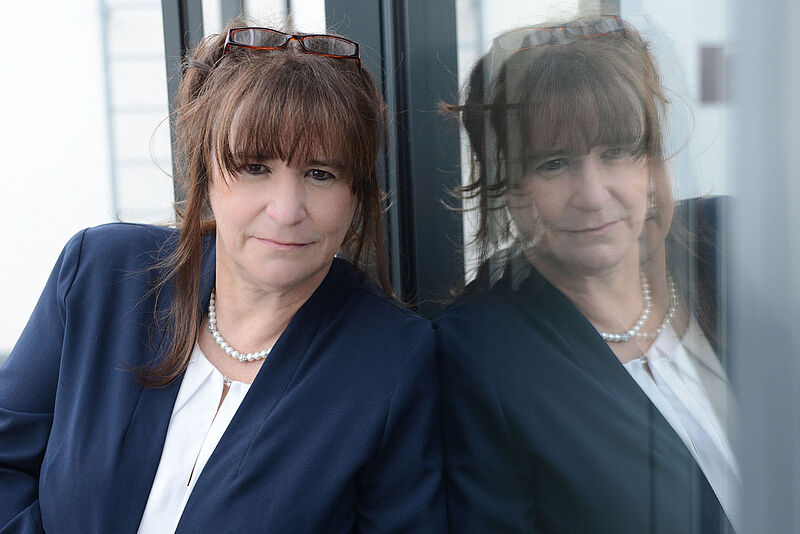 VUSR-Chefin Marija Linnhoff lehnt an eine Glaswand, wobei ihr Spiegelbild zu sehen ist