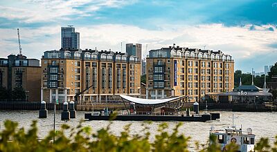 Moderner Gebäudekomplex des A & O Hostels direkt an der Themse in London mit Blick auf Fluss, Anlegestelle und vorbei fahrenden Booten