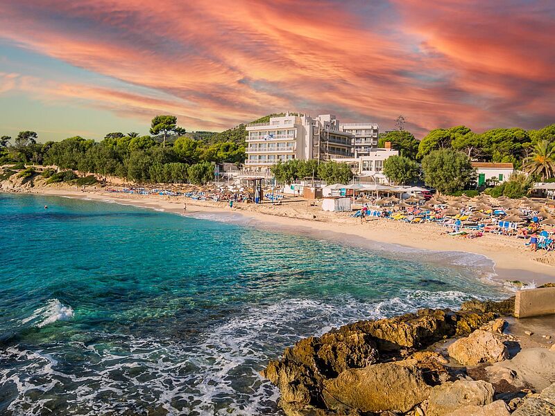 Ein Hotel steht am feinsandigen Strand auf Mallorca mit einer tollen Himmelsfärbung
