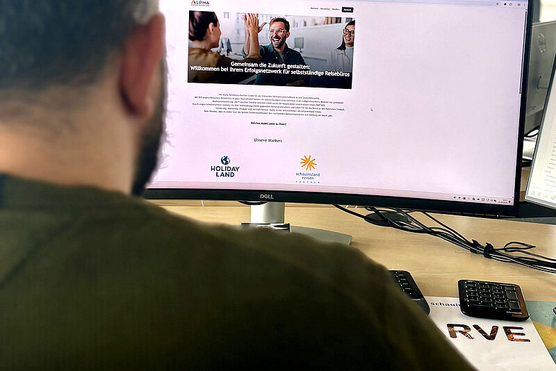 Computerbildschirm zeigt Alpha-Netzwerk-Website mit Welcome-Banner und Logos von Holiday Land und Schauinsland-Reisen als Partnermarken
