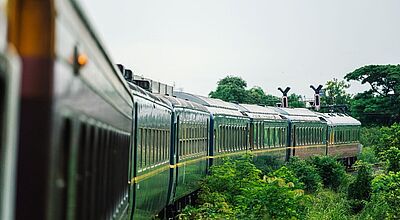 Der neue Luxuszug The Blue Jasmine führt Reisende in Thailand auf Routen abseits bekannter Pfade. Foto: The Blue Jasmine Außenansicht eines Zuges, der durch eine grüne Landschaft fährt.