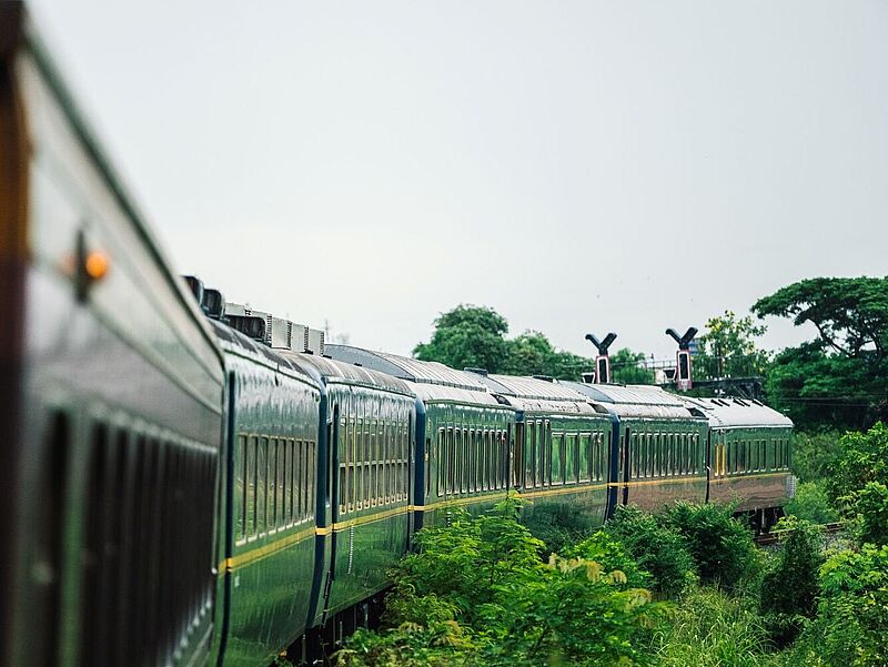 Der neue Luxuszug The Blue Jasmine führt Reisende in Thailand auf Routen abseits bekannter Pfade. Foto: The Blue Jasmine Außenansicht eines Zuges, der durch eine grüne Landschaft fährt.