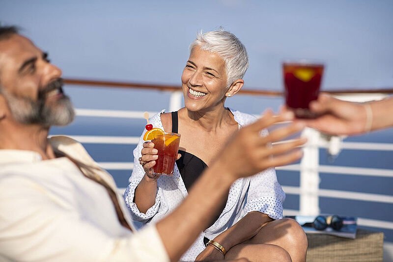 Auch Getränke sind Bestandteil des neuen Genusspakets Paar mit Drinks an Deck eines Kreuzfahrtschiffs