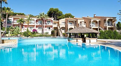 Mediterranes Hotel auf Mallorca mit palmengesäumtem Außenpool und Sonnenterrasse – entspannter Urlaub auf den sonnigen Balearen.