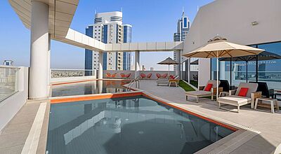 Rooftop-Pool im Hotel Barcelo in Manama, Bahrain mit Sonnenliegen, modernen Sitzbereichen und Blick auf die Skyline – luxuriöse Dachterrasse mit Stadtblick für erholsamen Aufenthalt im Nahen Osten.