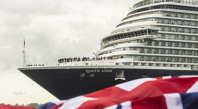 Bug eines englischen Kreuzfahrtschiffes mit einer britischen Flagge im Vordergrund.