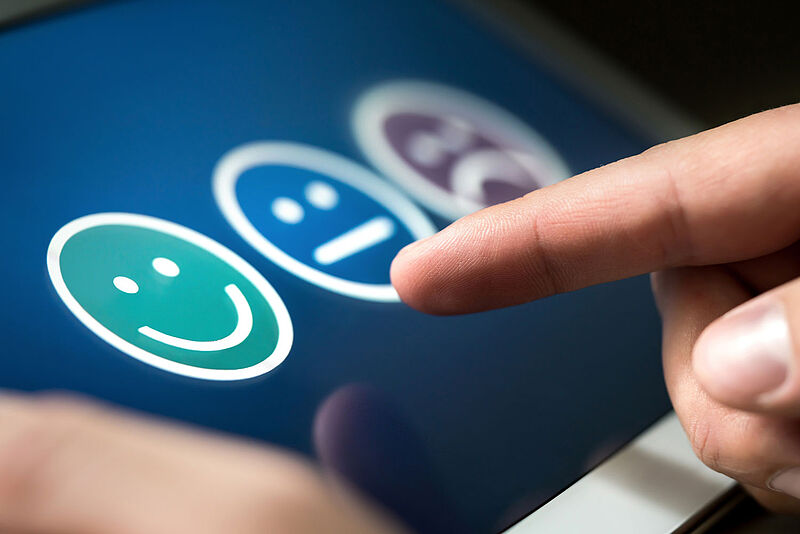 Finger tippt auf lächelndes Smiley auf einem Tablet