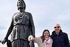 Ein Mann und eine Frau stehen rechts neben einer Statue und posieren für die Kamera