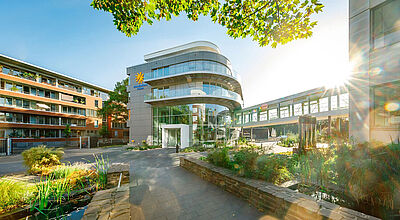 Außenaufnahme der mit viel Glas verkleideten modernen Zentrale des Reiseveranstalters Schauinsland, im Vordergrund ragen grüne Pflanzen ins Bild