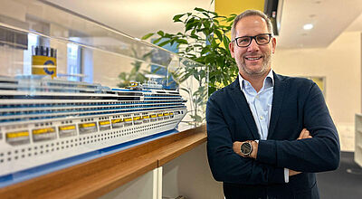Olaf Kistenmacher leitet seit Juni den Vertrieb in der Costa-Niederlassung in Hamburg. Foto: Costa Vertriebschef Olaf Kistenmacher neben einem Schiffsmodell im Büro von Costa Kreuzfahrten in Hamburg
