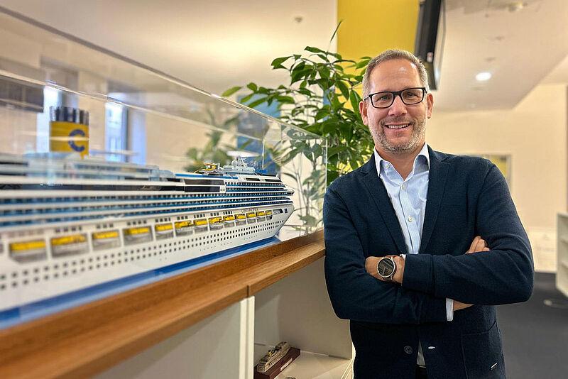 Olaf Kistenmacher leitet seit Juni den Vertrieb in der Costa-Niederlassung in Hamburg. Foto: Costa Vertriebschef Olaf Kistenmacher neben einem Schiffsmodell im Büro von Costa Kreuzfahrten in Hamburg