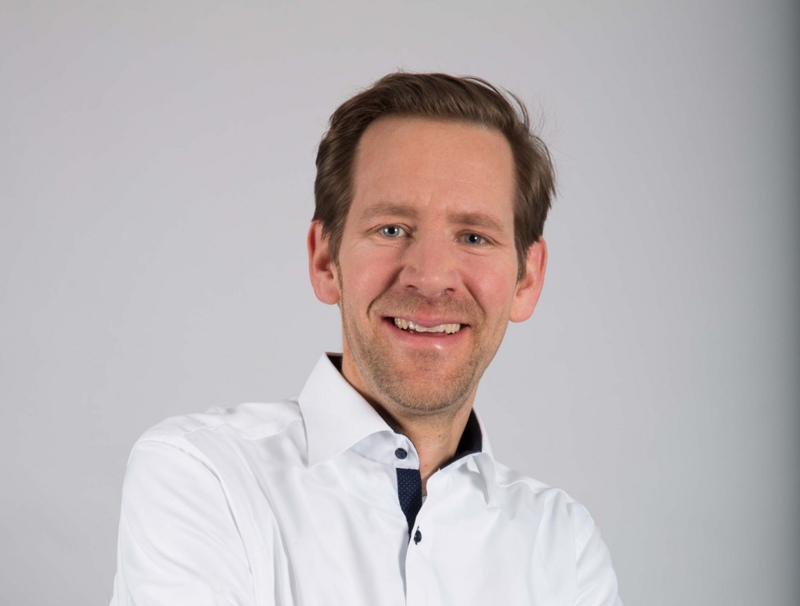 Mann in weißem Hemd lacht in die Kamera