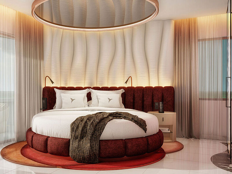 Ein rundes Bett mit einem Spiegel darüber in einem Hotelzimmer. Links ist ein Balkon mit Poolblik