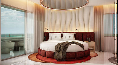 Ein rundes Bett mit einem Spiegel darüber in einem Hotelzimmer. Links ist ein Balkon mit Poolblik