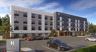 Ein mehrstöckiges Hotelgebäude, davor ein Parkplatz mit einigen Autos