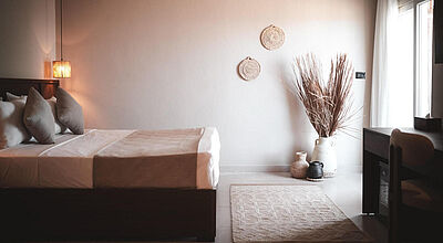 Modernes Hotelzimmer in Hurghada, Ägypten im Boho-Design, gemütlichem Doppelbett, natürlicher Dekoration und hellem Tageslicht 