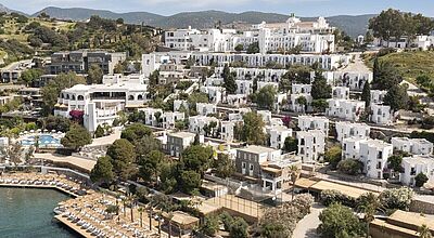 Luxuriöse Hotelanlage in Bodrum, Türkei mit weißen Villen im mediterranen Stil, Panorama-Blick auf das Meer, Privatstrand mit Sonnenliegen, Poolbereich und grüner Landschaft – perfektes Reiseziel für Urlaub, Entspannung und Strandferien.