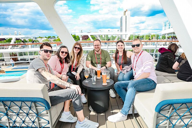Eine Gruppe Menschen auf einem Kreuzfahrtschiff lacht in die Kamera