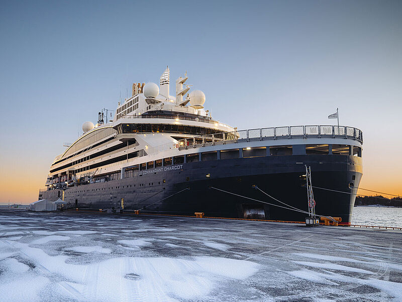 An der leicht verschneiten Pier in Helsinki liegt ein moderner Eisbrecher mit dunkelblauem Rumpf und weißem Aufbau