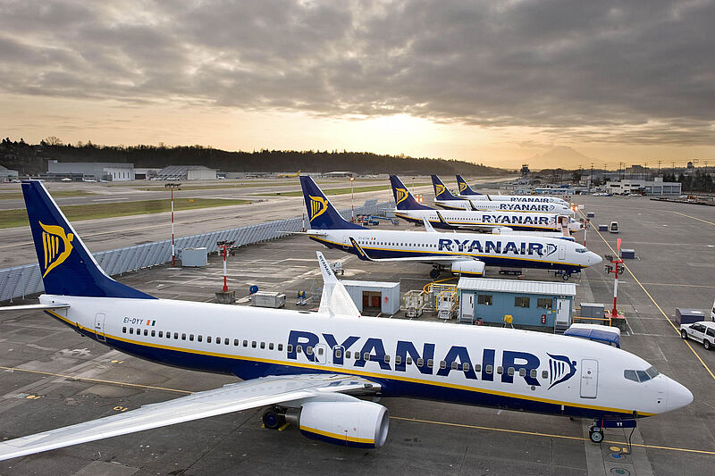 Mehrere weiß-blaue Flugzeuge des Billigfliegers Ryanair stehen nebeneinander auf dem Vorfeld eines Flughafens vor einem dramatischen Abendhimmel