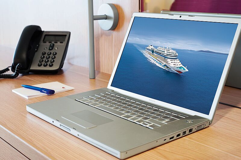 Ein Laptop, auf dem ein Aida-Schiff zu sehen ist. Naben ein Telefon