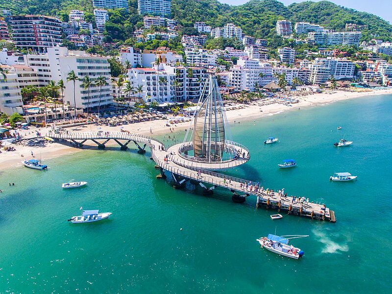 Luftaufnahme von Puerto Vallarta mit dem modernen Pier 'Malecón de los Muertos', Booten im türkisblauen Meer und Hotels entlang der Küste in Jalisco, Mexiko