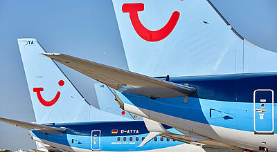 Nahaufnahme hellblauer TUI-Flieger, die an einem Airport in Parkposition stehen.