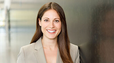 Porträtfoto einer freundlichen, lachenden jungen Frau im Business Outfit