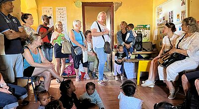 Kleine Kindergartenkinder präsentieren stolz ihre neuen Kuscheltiere. Die bunten Wandmalereien im Hintergrund spiegeln die fröhliche Atmosphäre der Einrichtung wider.