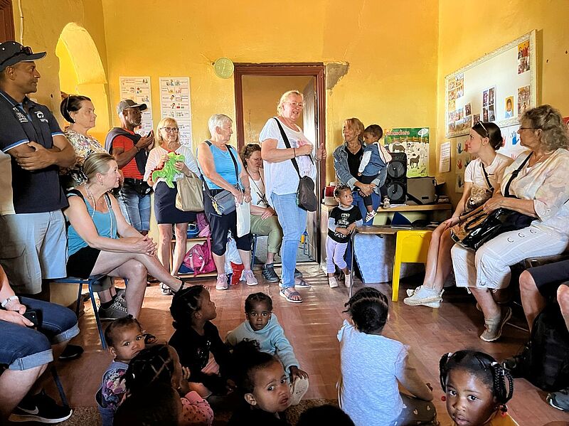 Seit 2023 unterstützt Annette Eilers von der TUI Travel Star Reiselounge Eilers das Projekt Kleine Eentjie in Südafrika und war bereits mehrfach vor Ort Kleine Kindergartenkinder präsentieren stolz ihre neuen Kuscheltiere. Die bunten Wandmalereien im Hintergrund spiegeln die fröhliche Atmosphäre der Einrichtung wider.