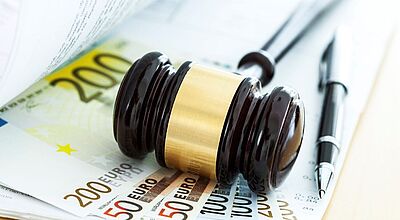 Richterhammer auf Eurobanknoten und Dokumenten, daneben ein Stift.