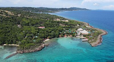Das Sol Roatan Media Luna Resort liegt an der Südküste der Karibikinsel Roatan. Foto: Melia Hotels International Luftaufnahme der tropischen Insel Roatan in Honduras mit üppigem Regenwald, türkisblauem Karibikmeer und einem idyllisch gelegenen Strandresort – beliebtes Reiseziel für Taucher und Badeurlauber in Mittelamerika.