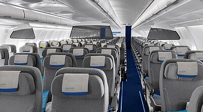 Innenansicht einer Flugzeugkabine von Discover Airlines in der Premium Economy Class mit grauen Sitzen, blauen Akzenten und Kopfstützenbezügen mit dem Airline-Logo, geordnet in mehreren Reihen mit Mittelgang