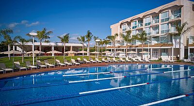 Im Zafiro Alzinar Mar gibt es nun einen halb-olympischen Pool. Foto: Zafiro Hotels Halbolympischer Pool mit abgeteilten Bahnen, im Hintergrund Liegen und ein Hotelgebäude