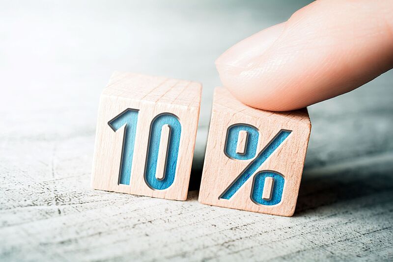 Eine Hand dreht zwei Holzklötze, auf denen 10 Prozent steht